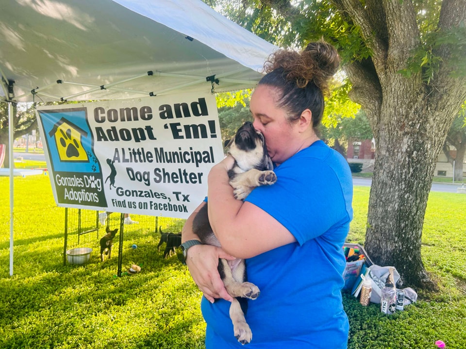 Volunteer hugging puppy under tent